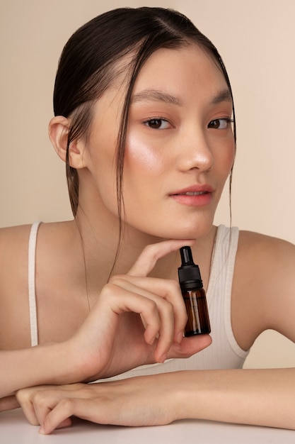 Foto gratuita mujer coreana de tiro medio posando con botella de suero