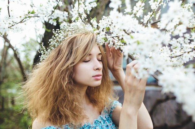Mujer con una corona oliendo los árboles en flor