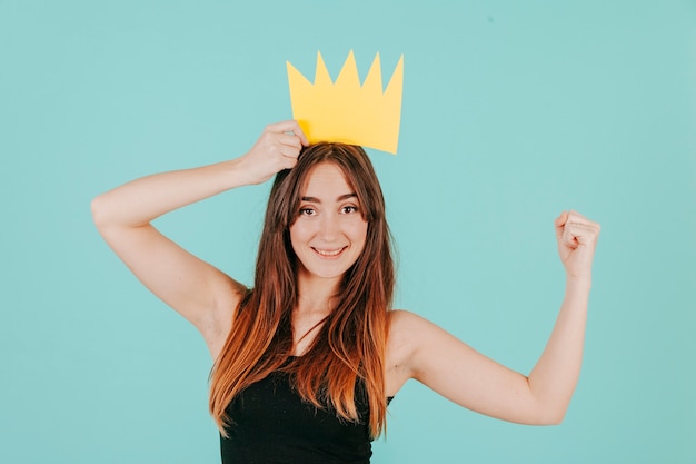 Mujer en corona de papel mostrando músculo