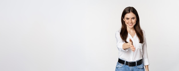 Mujer corporativa amigable sonriente que extiende el brazo para un apretón de manos saludando a un socio comercial