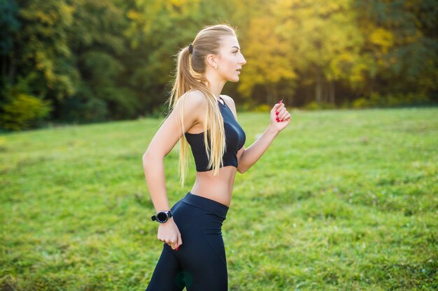 Mujer para correr corriendo en el parque bajo el sol en un hermoso día de verano. Modelo de fitness deportivo entrenamiento de etnia caucásica al aire libre para maratón.