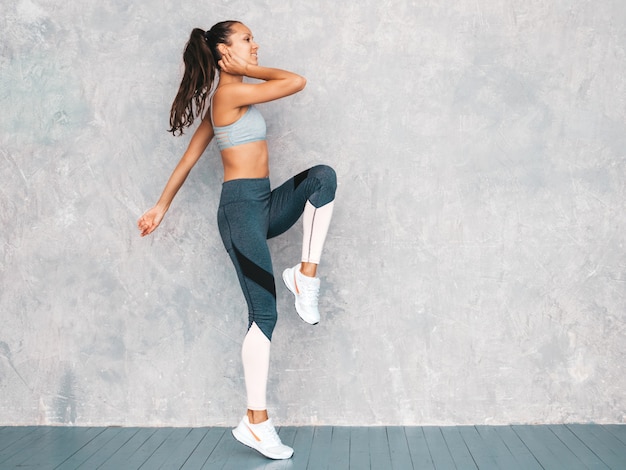 Mujer corriendo en estudio cerca de la pared gris