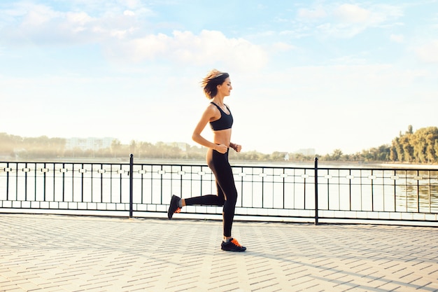 Mujer corriendo por el lago al atardecer