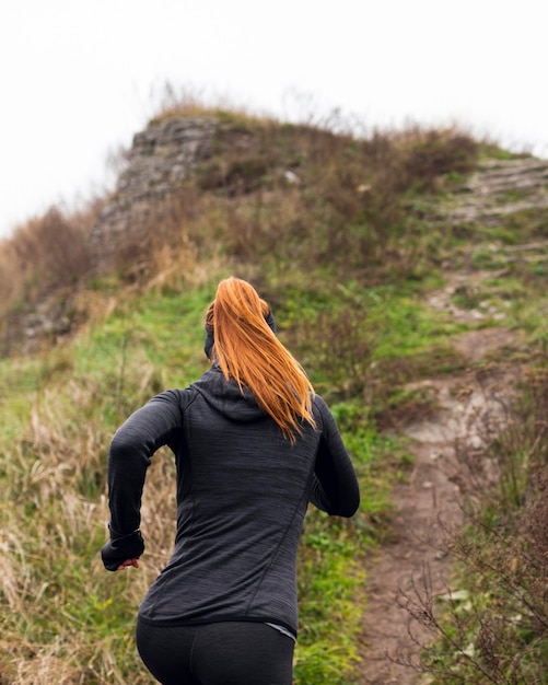 Mujer corriendo en la naturaleza desde atrás shot