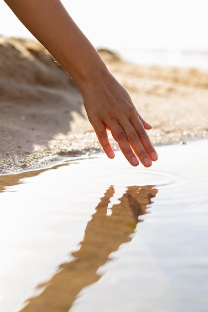 Mujer corriendo su mano a través del agua en la playa.