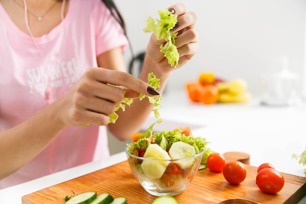 Foto gratuita la mujer corta la ensalada verde en la cocina