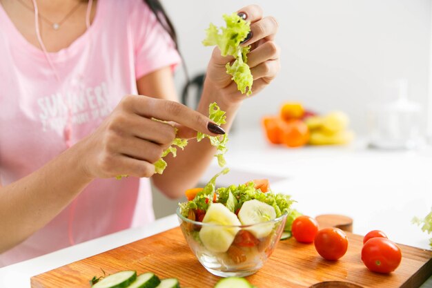 La mujer corta la ensalada verde en la cocina