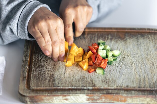 Foto gratuita una mujer corta verduras en una tabla de cortar