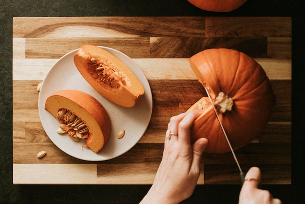 Mujer cortando calabaza para la cena de Acción de Gracias fotografía de comida flatlay