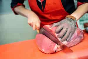 Foto gratuita mujer cortando carne fresca en una carnicería con guante de malla de seguridad de metal