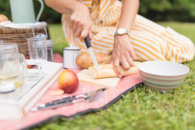 Mujer cortando pan con cuchillo en picnic