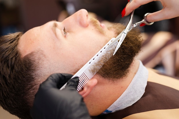 Foto gratuita mujer cortando el primer plano de barba de un cliente