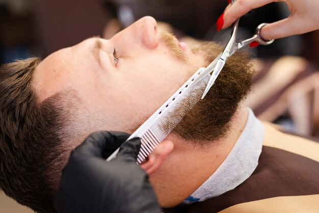 Mujer cortando el primer plano de barba de un cliente