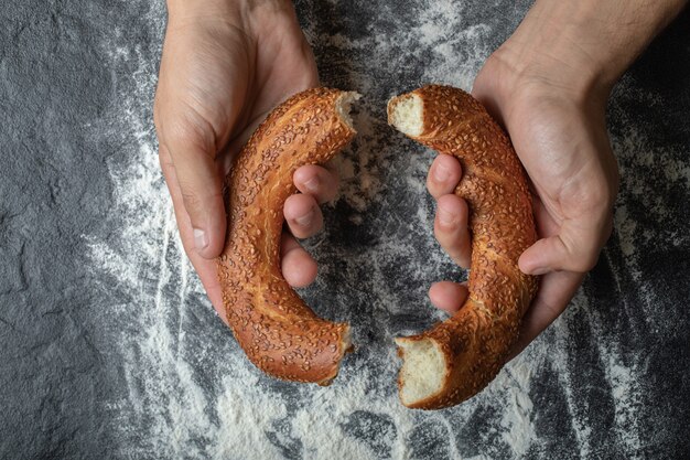 Mujer cortando simit turco con la mano.