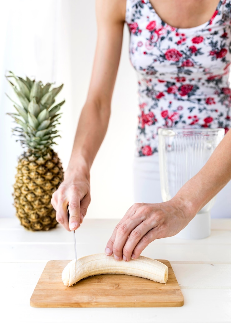 Foto gratuito mujer cortando un tiro mediano de plátano