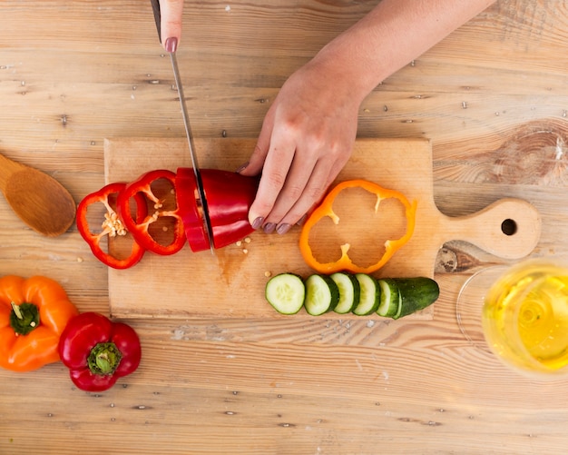 Mujer cortando verduras en una bandeja de madera