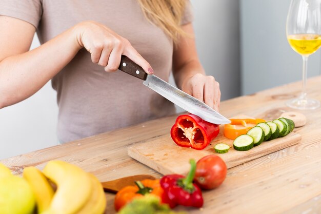 Mujer cortando verduras sobre un soporte de madera