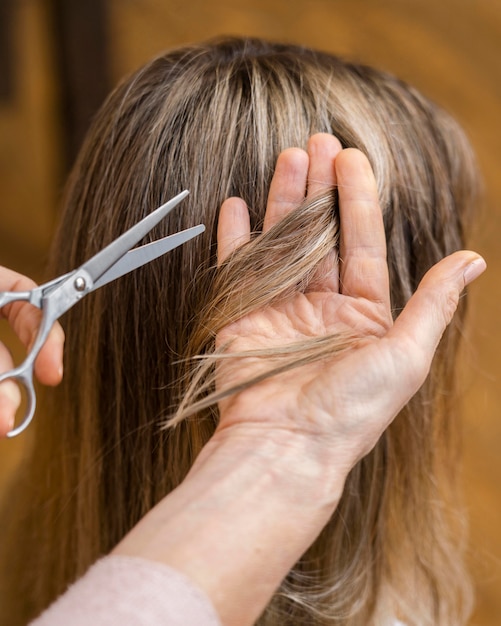 Mujer cortándose el pelo en casa por esteticista