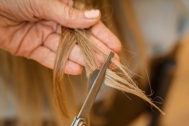 Mujer cortándose el pelo en casa por peluquero