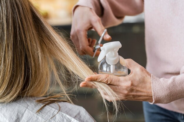 Mujer cortándose el pelo en casa por peluquero