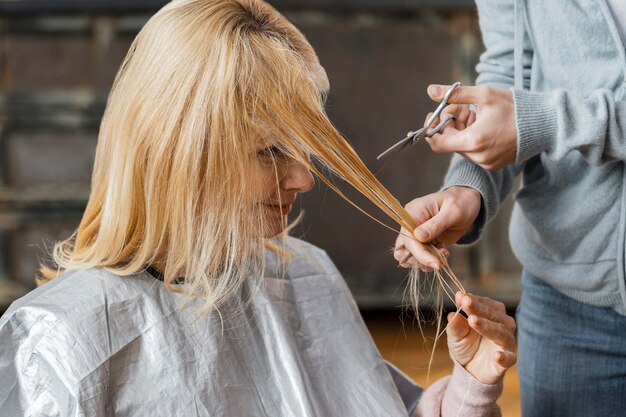 Mujer cortándose el pelo por peluquero en casa