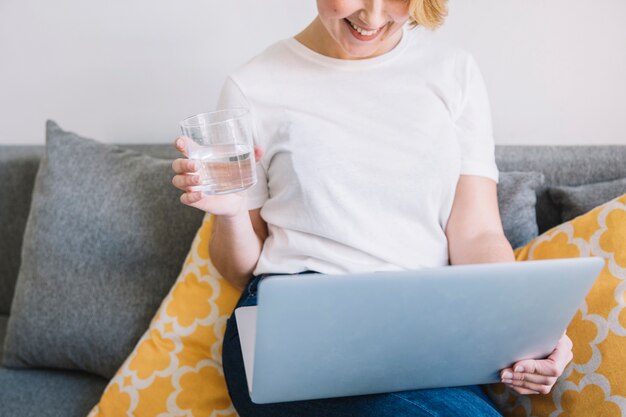 Mujer de la cosecha con agua usando la computadora portátil