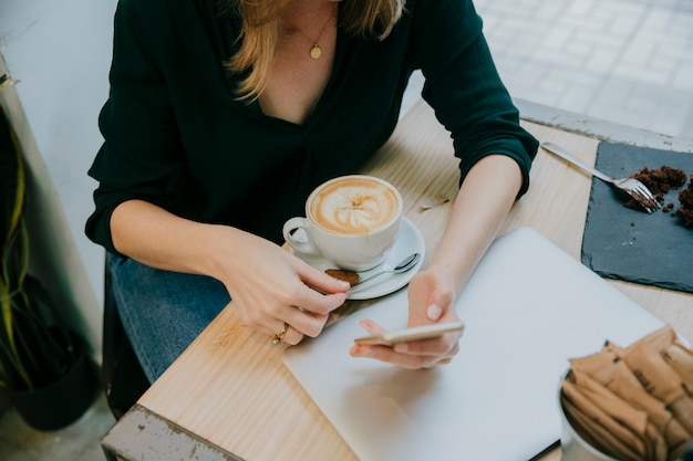 Mujer de la cosecha con café con smartphone