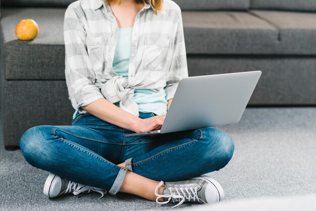 Mujer de la cosecha con la computadora portátil cerca del sofá