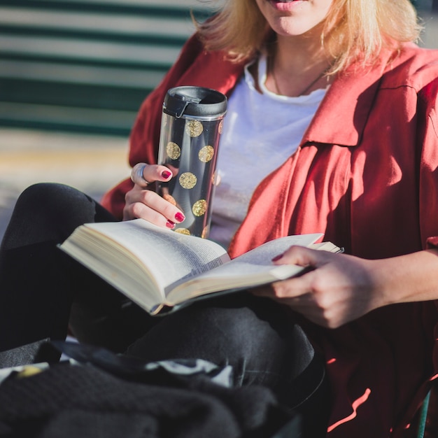 Mujer de cosecha disfrutando de libro y bebida