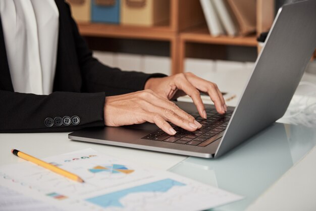 Mujer de cosecha escribiendo en la computadora portátil