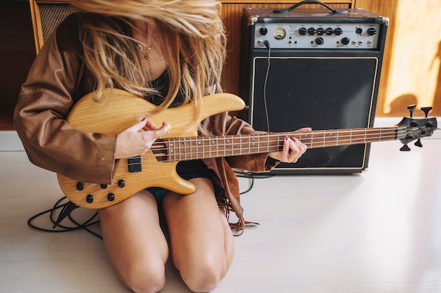 Mujer de la cosecha con la guitarra cerca del amplificador