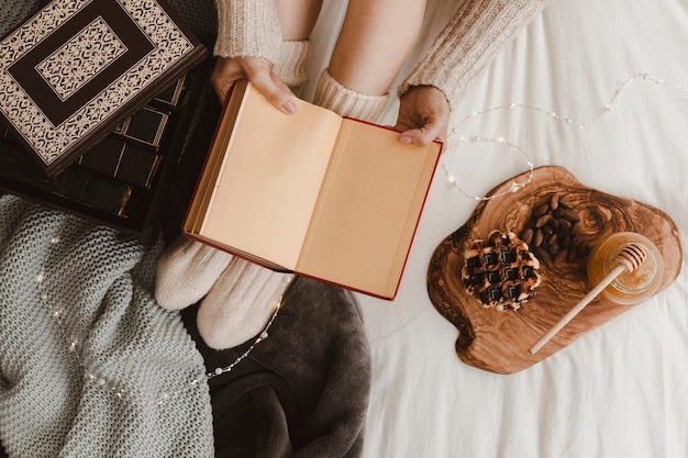 Mujer de la cosecha con el libro cerca de la galleta y la miel