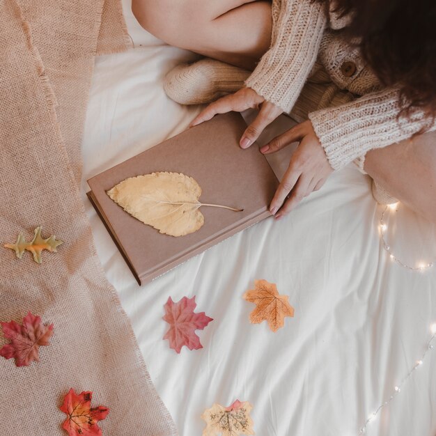 Mujer de la cosecha con el libro cerca de las hojas de otoño