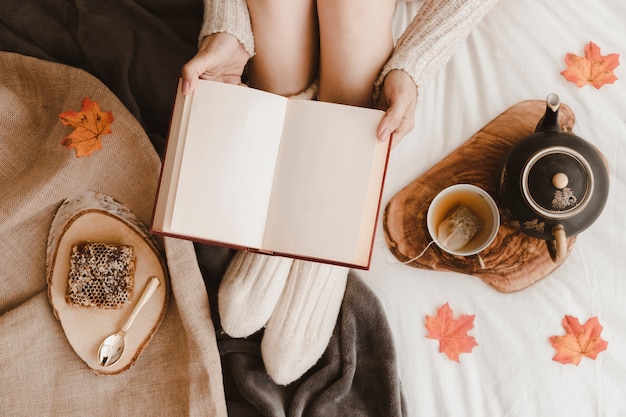 Mujer de la cosecha con el libro cerca del té y el panal