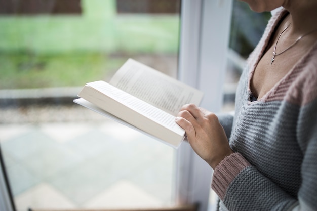 Mujer de la cosecha con el libro cerca de la ventana