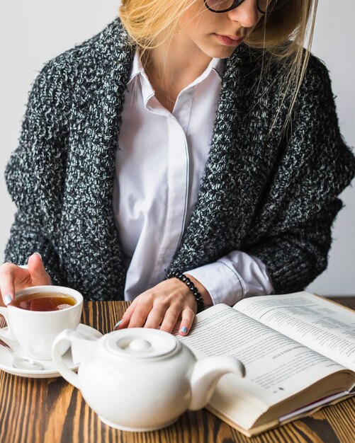 Mujer de la cosecha con el libro de lectura del té