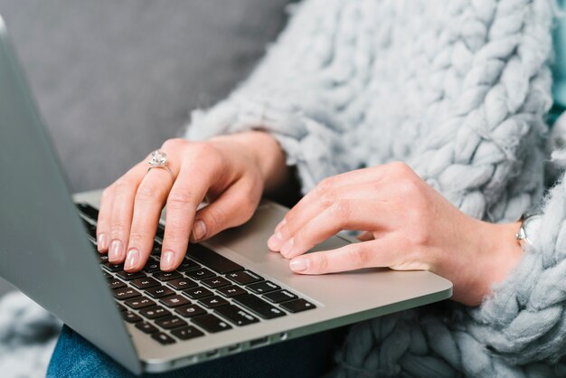 Mujer de la cosecha en manta que usa la computadora portátil