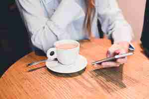 Foto gratuita mujer cosecha navegación smartphone en mesa de restaurante