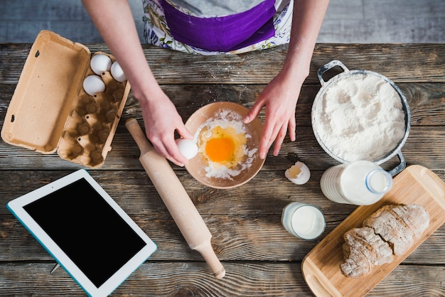 Mujer de la cosecha que agrega los huevos a la harina