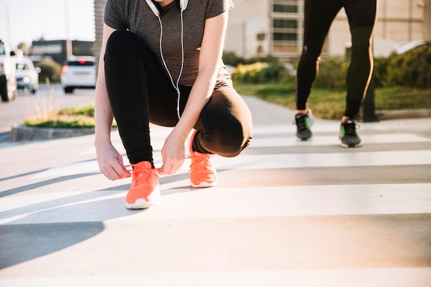 Mujer de la cosecha que ata cordones en el entrenamiento