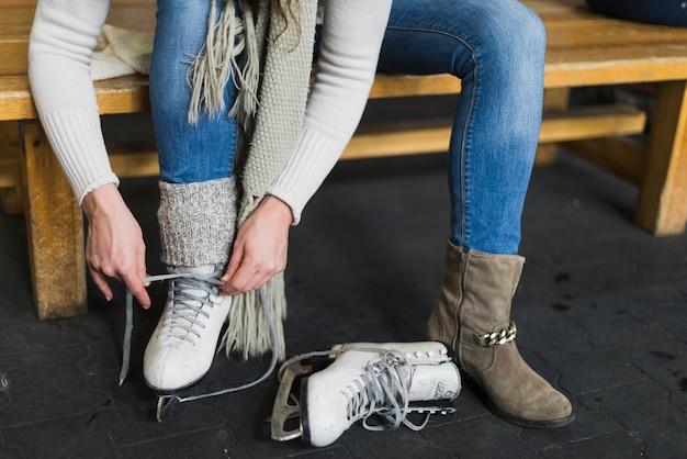 Mujer de la cosecha que ata cordones en patines de hielo