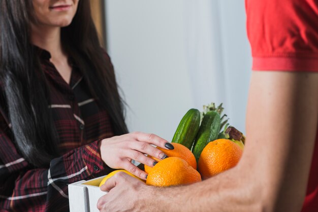 Mujer de la cosecha que comprueba las frutas entregadas por el mensajero