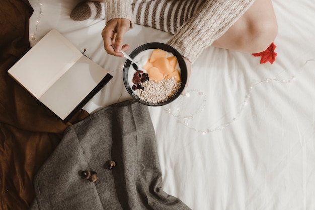 Mujer de la cosecha que desayuna cerca del libro