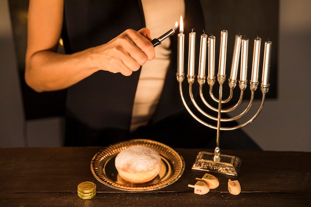 Mujer de la cosecha que enciende velas en menorah