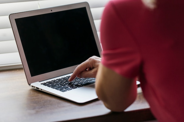 Foto gratuita mujer de la cosecha que navega la computadora portátil cerca de la ventana