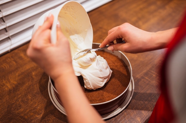 Mujer de la cosecha que pone la crema en la torta