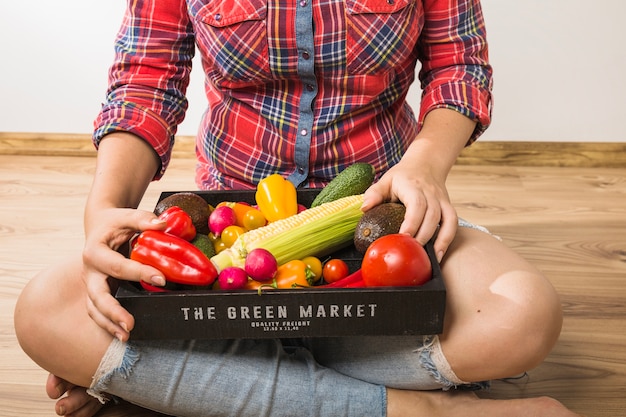 Mujer de la cosecha que sostiene la plataforma llena de verduras