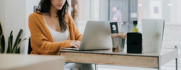 Mujer de la cosecha que usa la computadora portátil en café