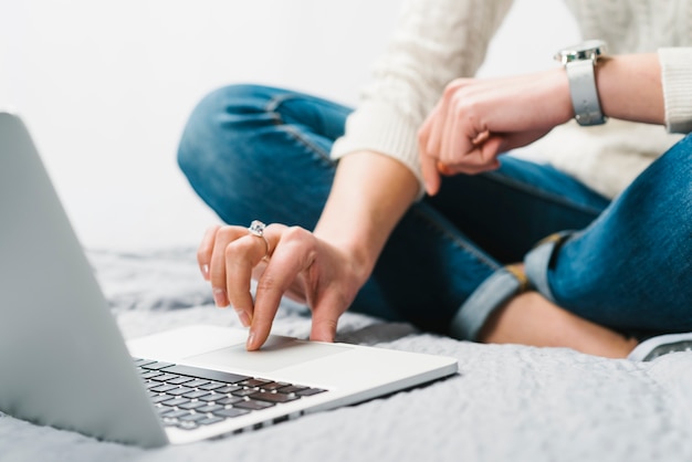 Mujer de la cosecha que usa la computadora portátil en cama