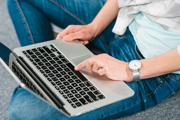 Mujer de la cosecha que usa la computadora portátil moderna en piso